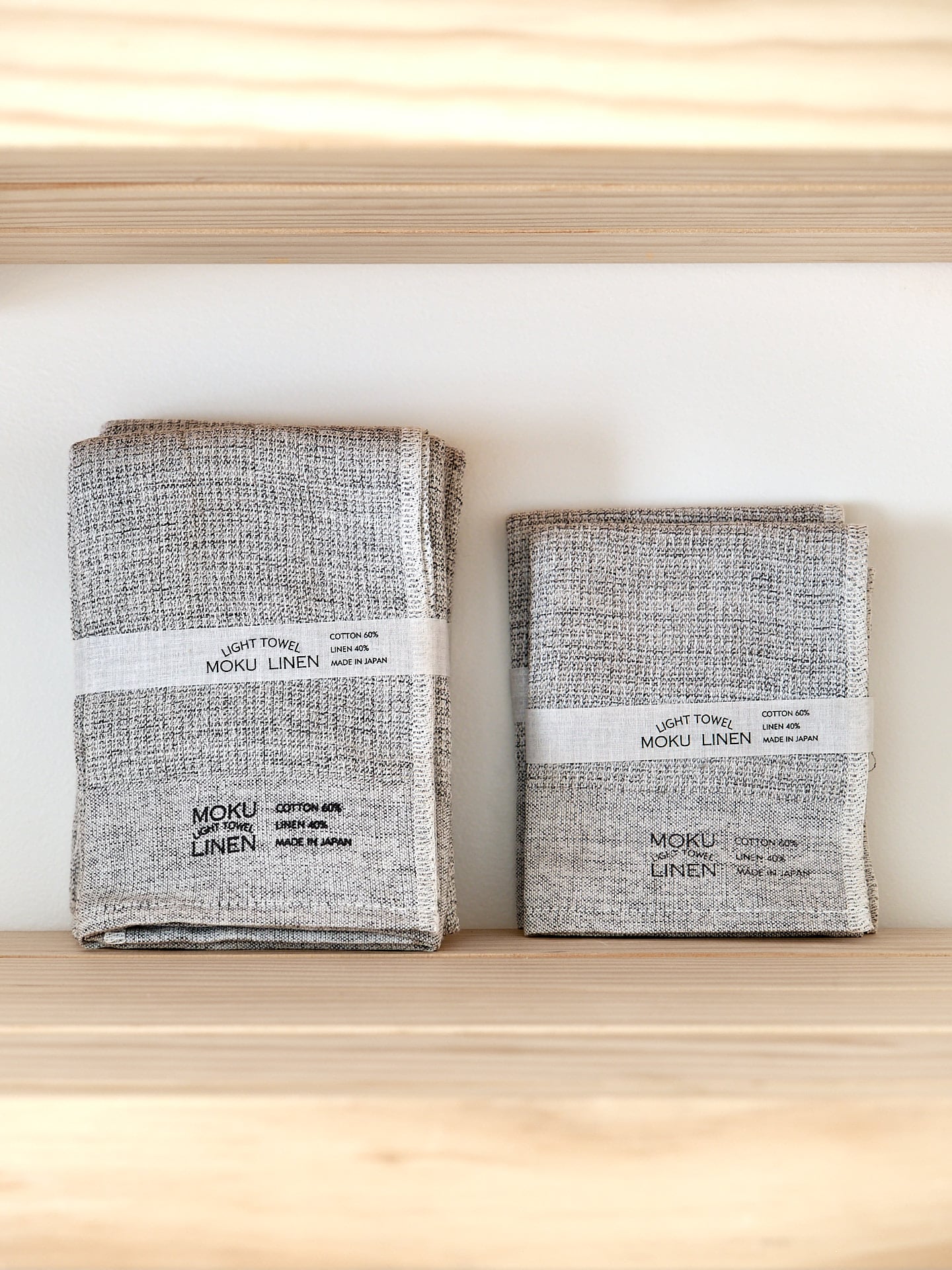 Two Kontex Moku Linen Lightweight Towels – Charcoal sitting on a wooden shelf.