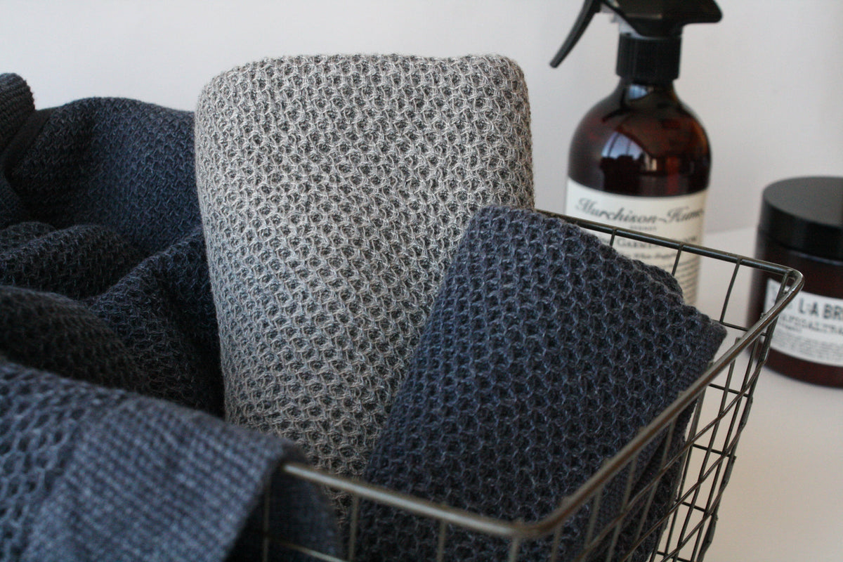 Vintage Waffle Towels by Kontex with a honeycomb waffle weave in a metal basket next to toiletry bottles.