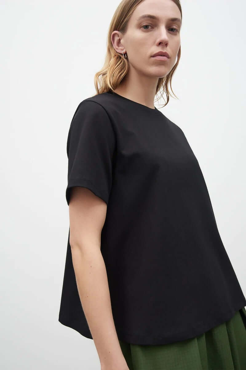 The model is wearing a Kowtow A-Line Tee - Black with green pleats.