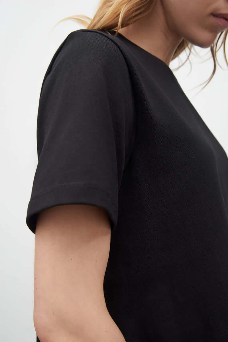 The back view of a woman wearing a Kowtow A-Line Tee – Black.