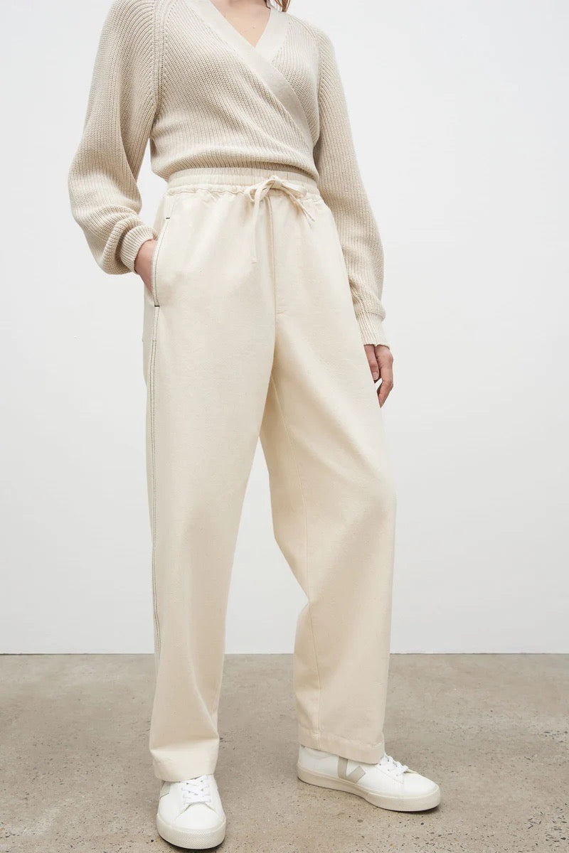 The model is wearing a beige sweater and Kowtow Blake Pants – Greige.