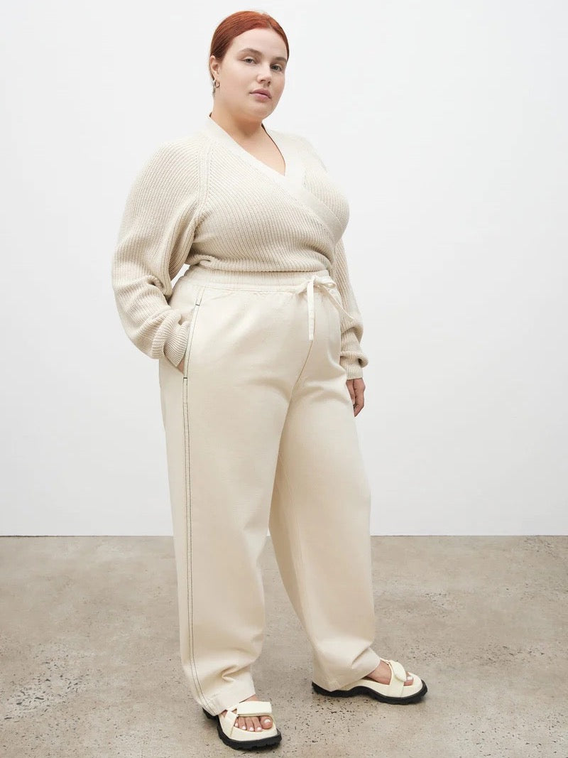 The model is wearing a Kowtow Blake Pants – Greige sweater and jogging pants.