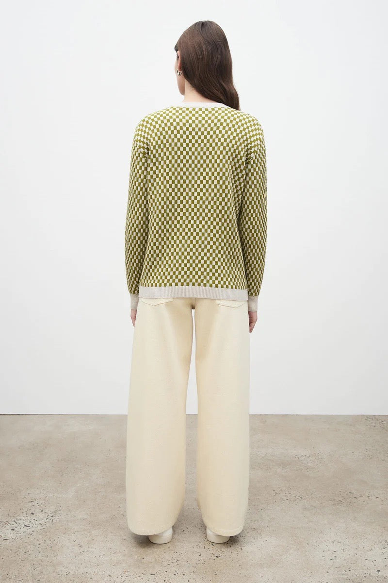 The back view of a woman wearing a Kowtow Checkerboard Knit Crew – Lawn Check sweater and beige wide leg pants.