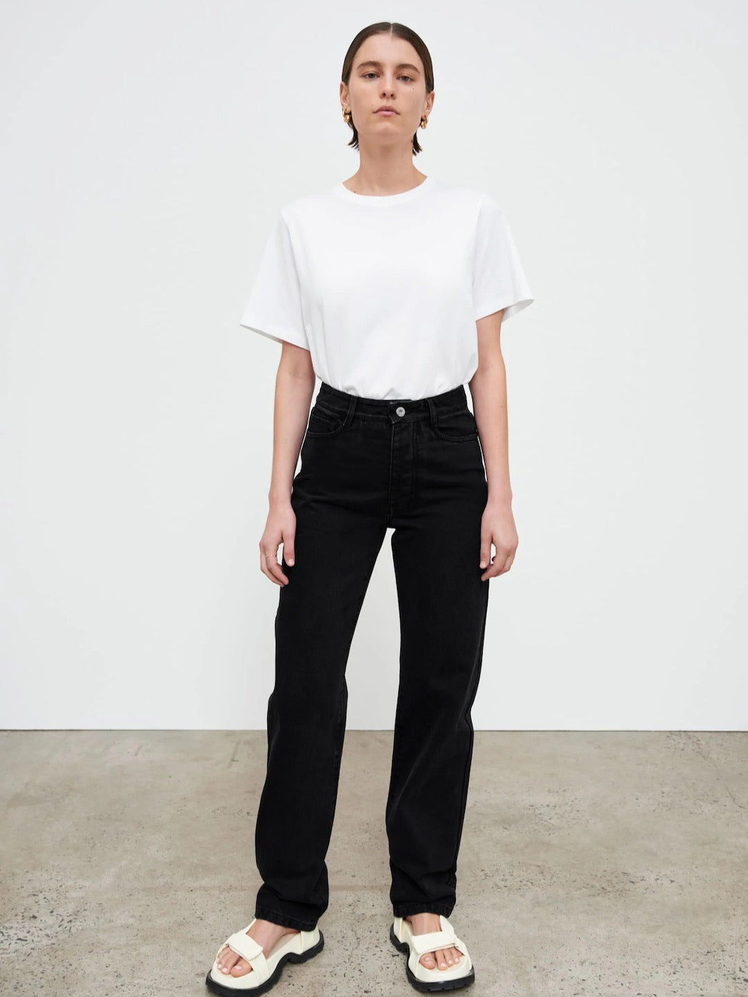 A woman wearing Classic Jeans – Black Denim by Kowtow and a white t-shirt.