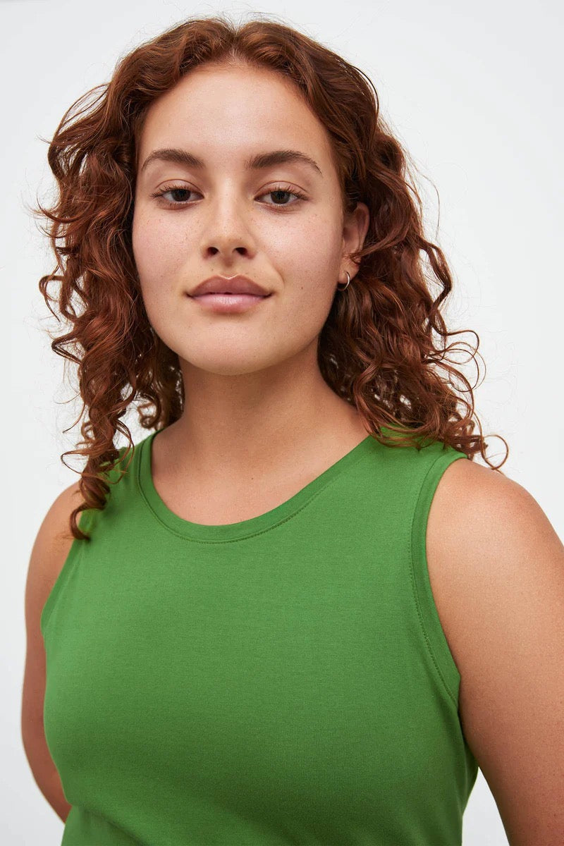 A woman in a Kowtow Cross Back Singlet - Bright Green posing for a photo.