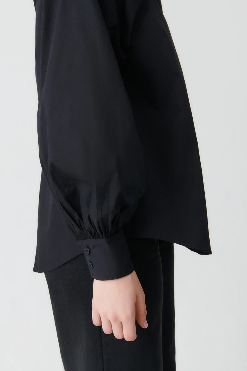The back view of a woman wearing a Kowtow Ella Shirt - Black.