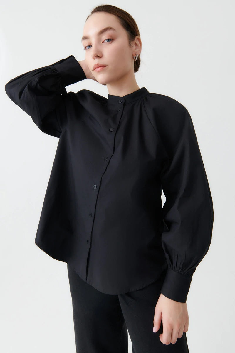 A model wearing the Ella Shirt - Black by Kowtow and black pants.