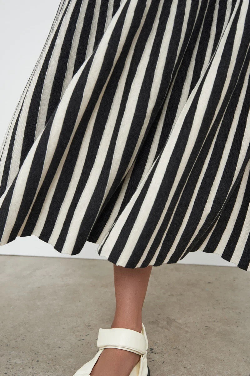 A woman wearing a Kowtow Field Skirt - Charcoal Skirt and white sandals.