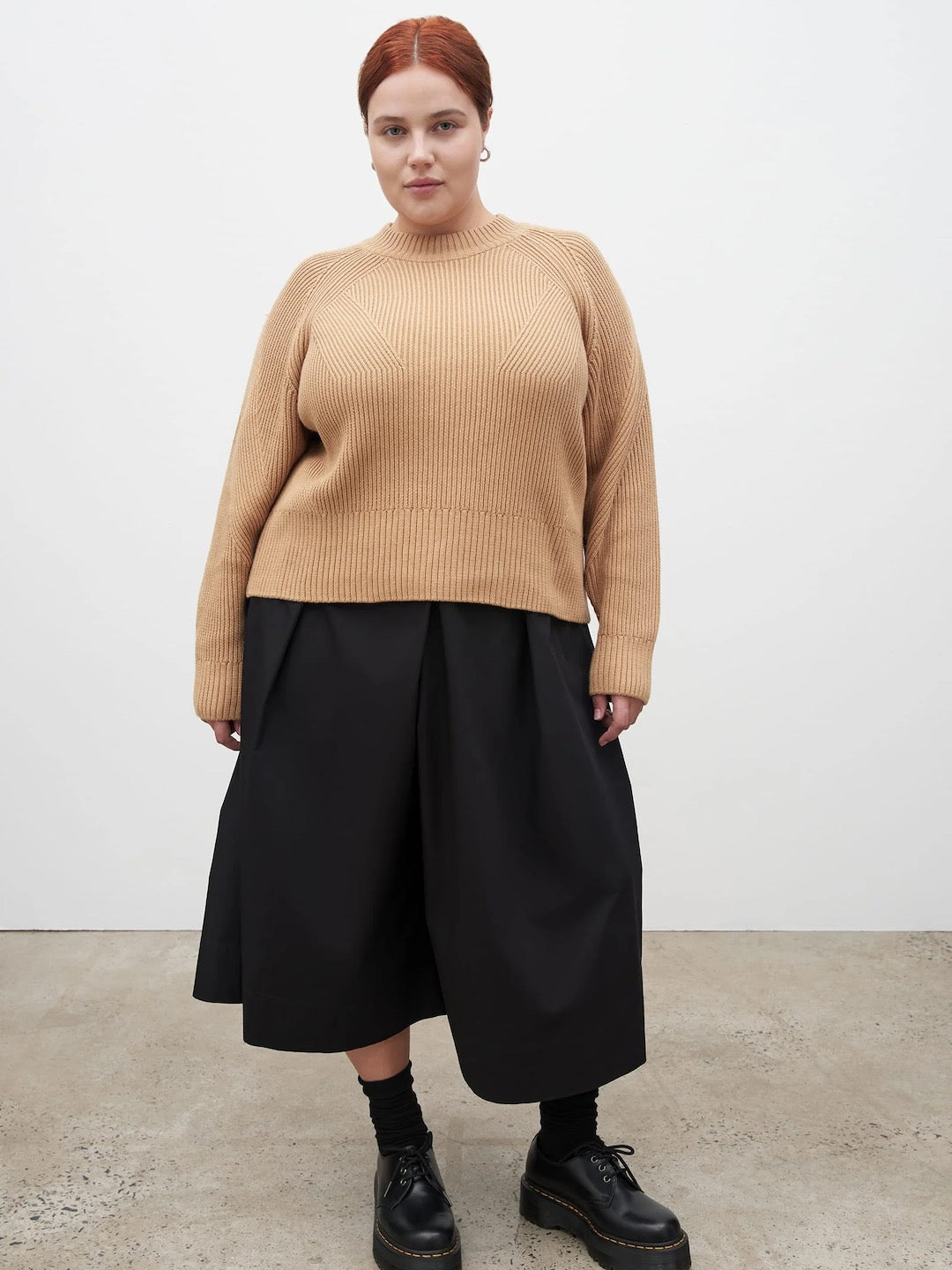 The model is wearing a Henri Crew - Beige sweater and black skirt by Kowtow.