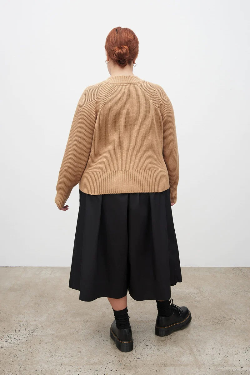 The back of a woman wearing a Kowtow camel Henri Crew - Beige sweater and black skirt.