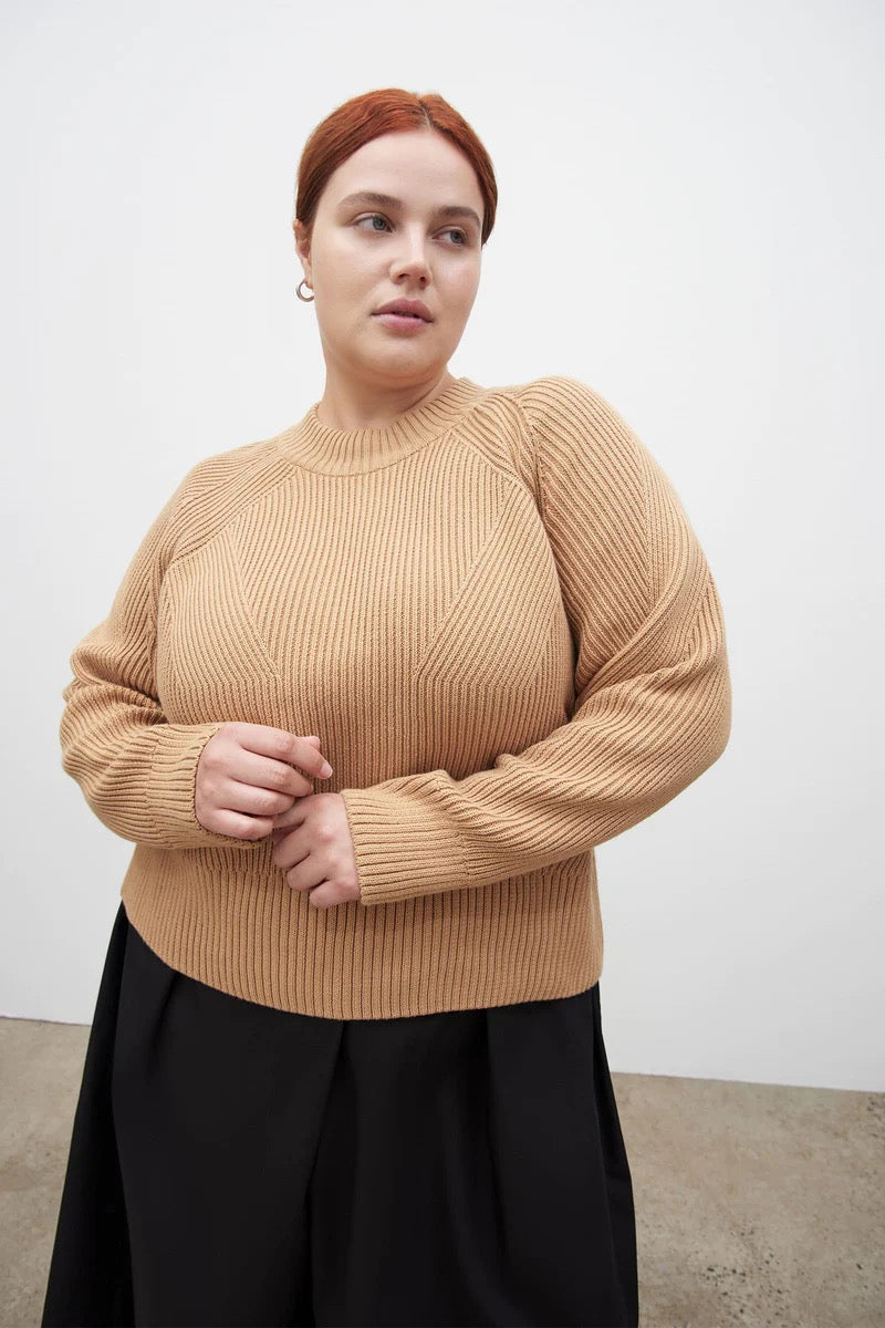 A model wearing a Henri Crew - Beige sweater and black pants by Kowtow.