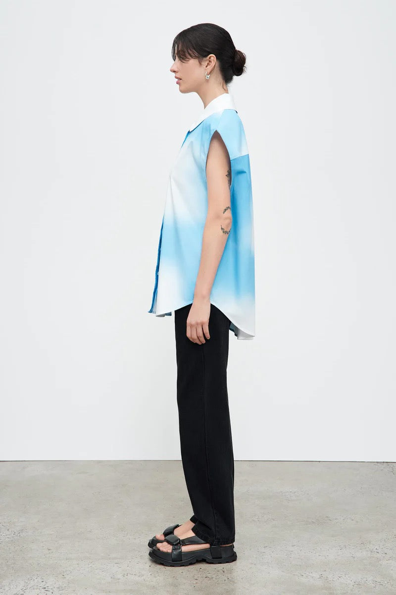 A woman wearing a Play Top - Cloud by Kowtow and black pants.