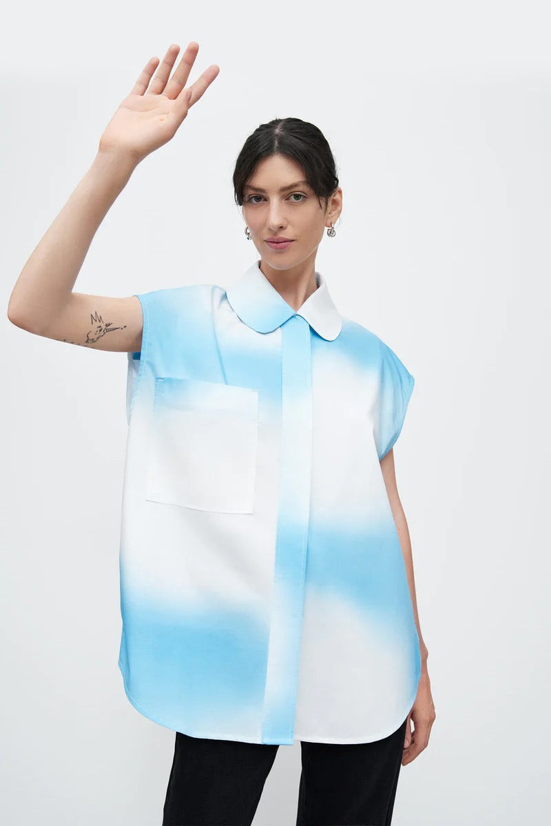 A woman wearing a Kowtow Play Top - Cloud shirt and waving her hand.