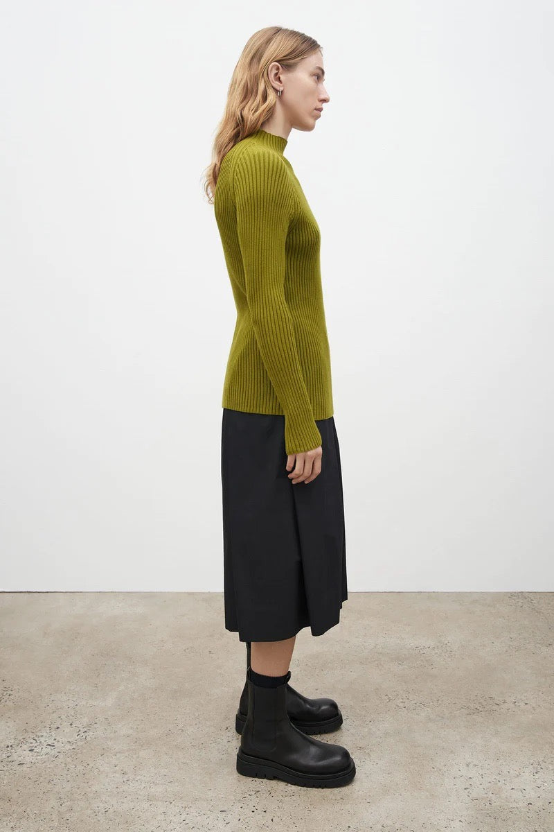 The model is wearing a Kowtow Row Top - Lawn sweater and black skirt.