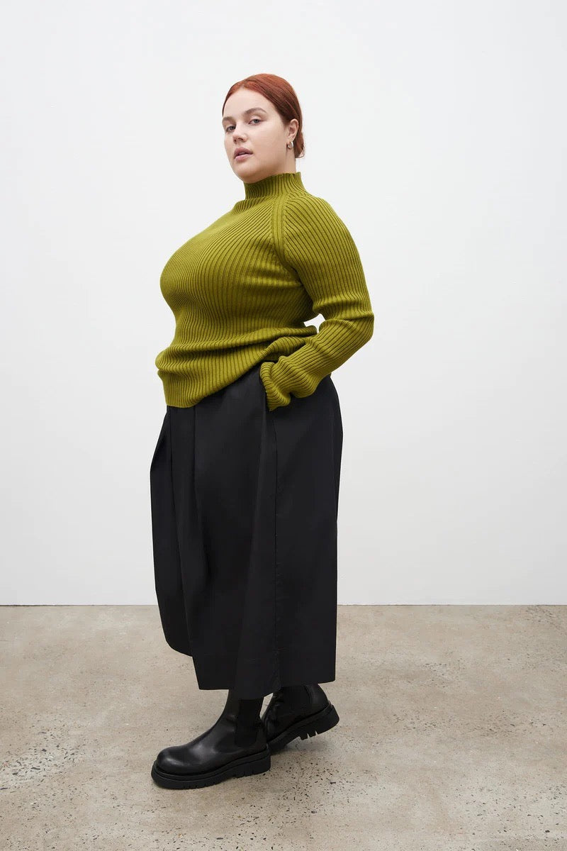 A woman wearing a Row Top - Lawn by Kowtow and black skirt.