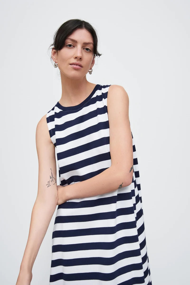The model is wearing a Rugby Tank Swing Dress – Navy White Stripe by Kowtow.