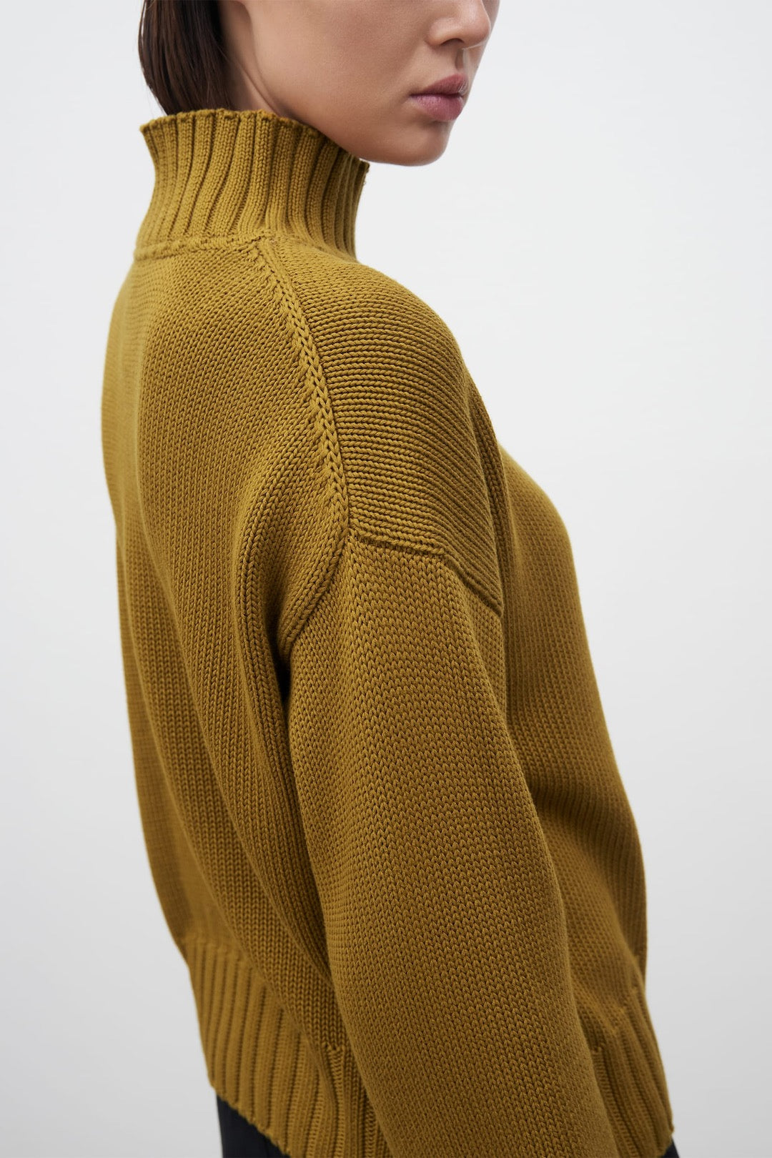 The back view of a woman wearing a Kowtow Staple Sweater – Chartreuse.