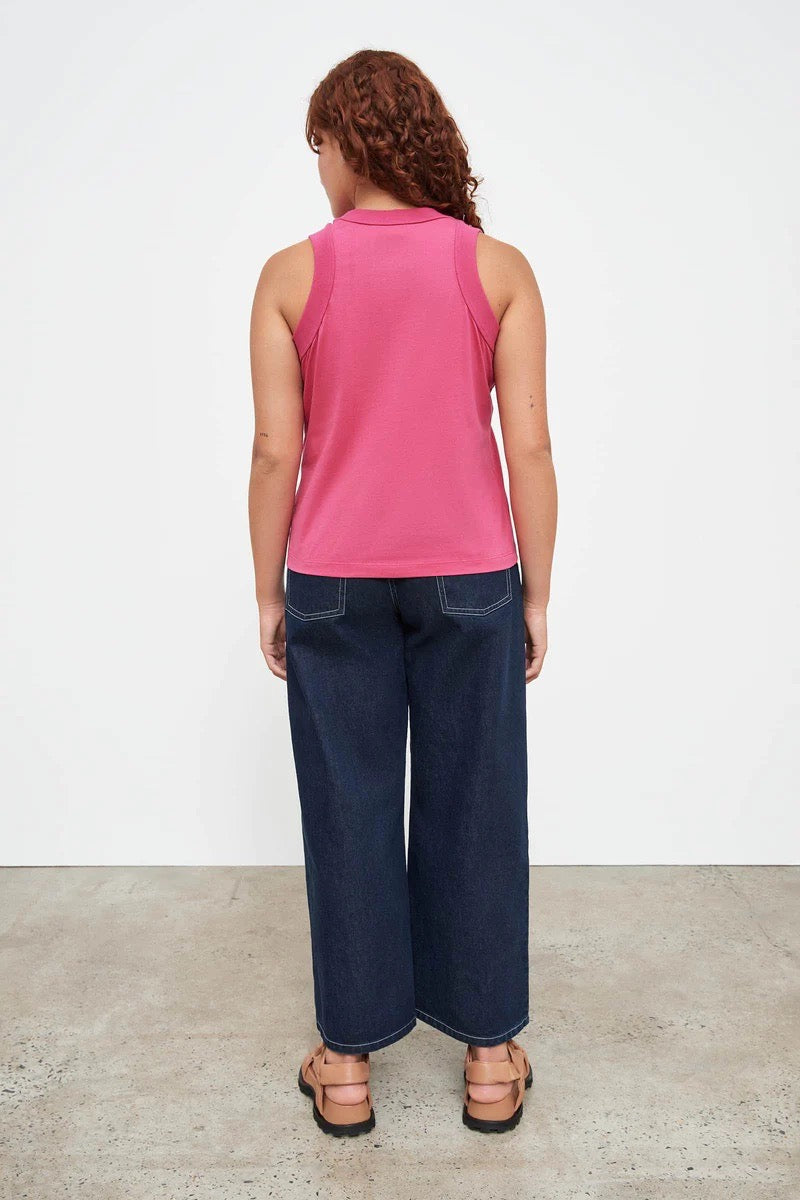 The back view of a woman wearing a Kowtow Fuchsia tank top and jeans.