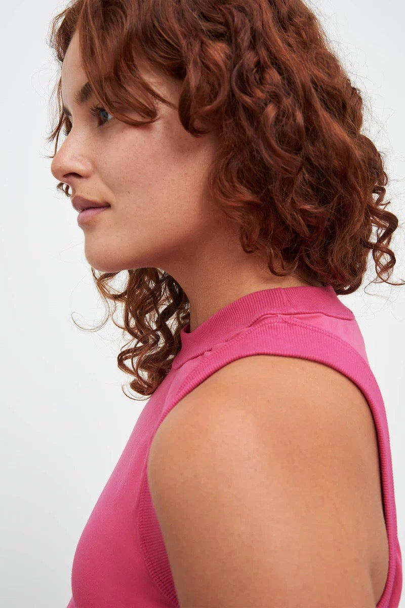 A woman wearing a Kowtow Tank Top - Fuchsia with curly hair.