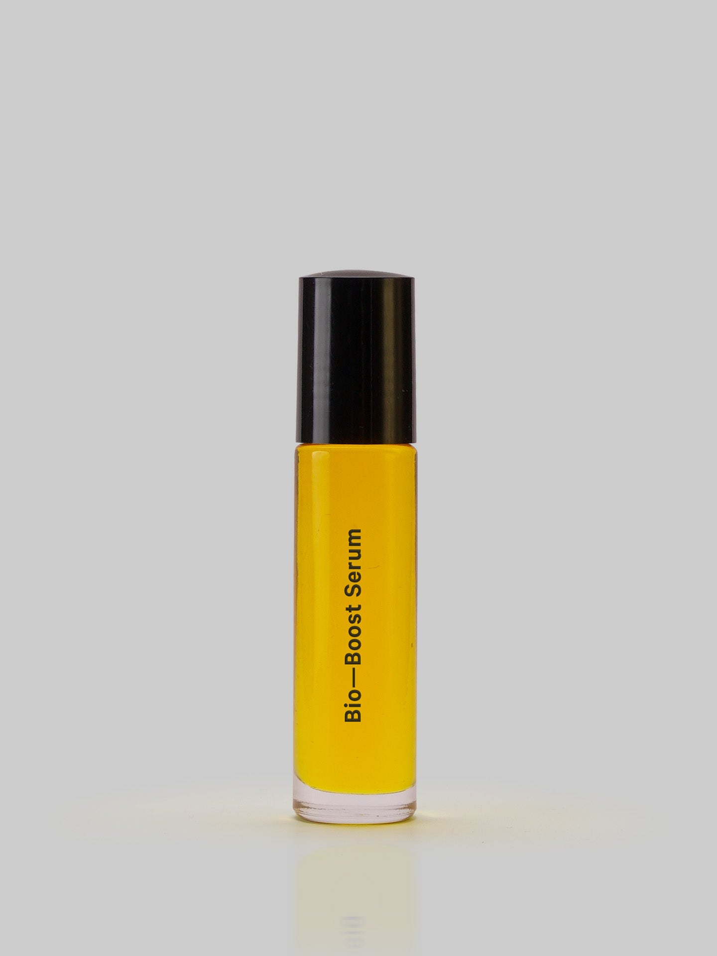 A yellow Bio-Boost – Serum bottle with a black cap on a grey background from MARYSE.