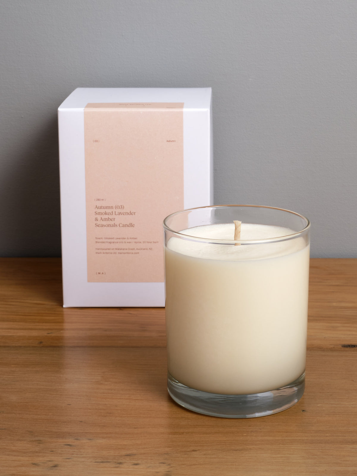 A Mark Antonia Seasonal Candle (2.0) – Autumn sitting on a wooden table next to a box.