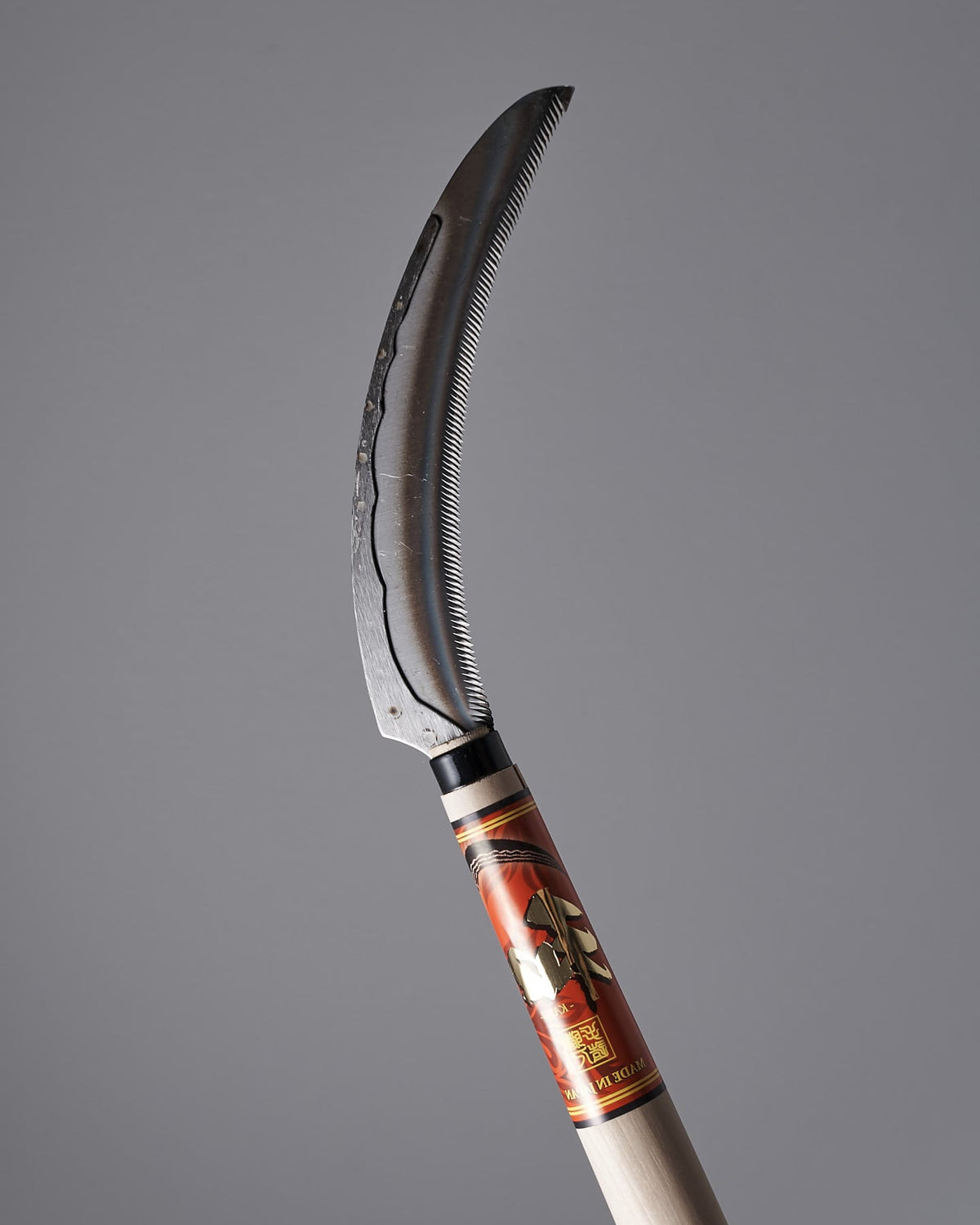 A Maruyoshi Flax Cutter with a wooden handle on a gray background.