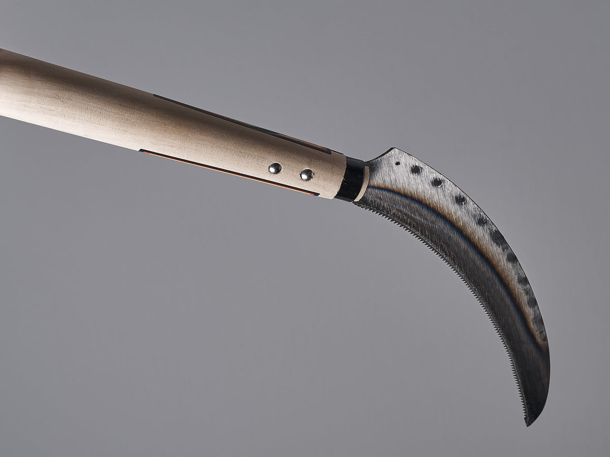 A Maruyoshi Flax Cutter with a wooden handle on a gray background.