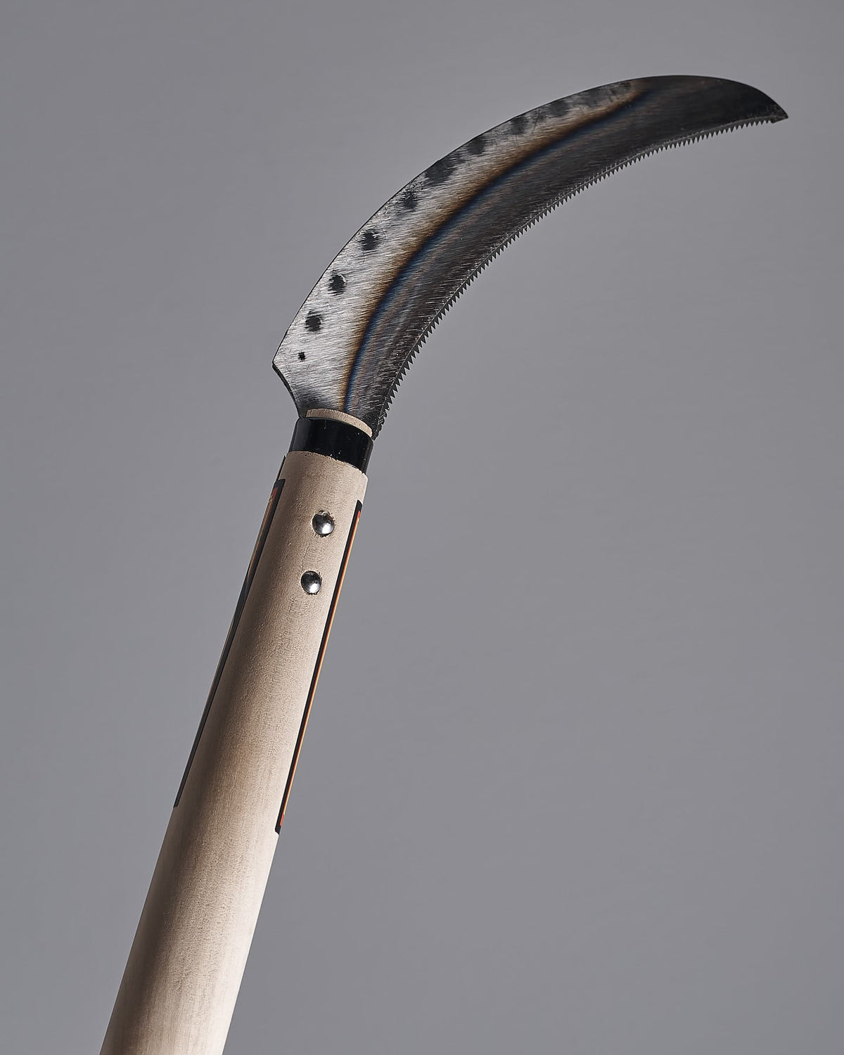 A Maruyoshi Flax Cutter with a wooden handle on a gray background.