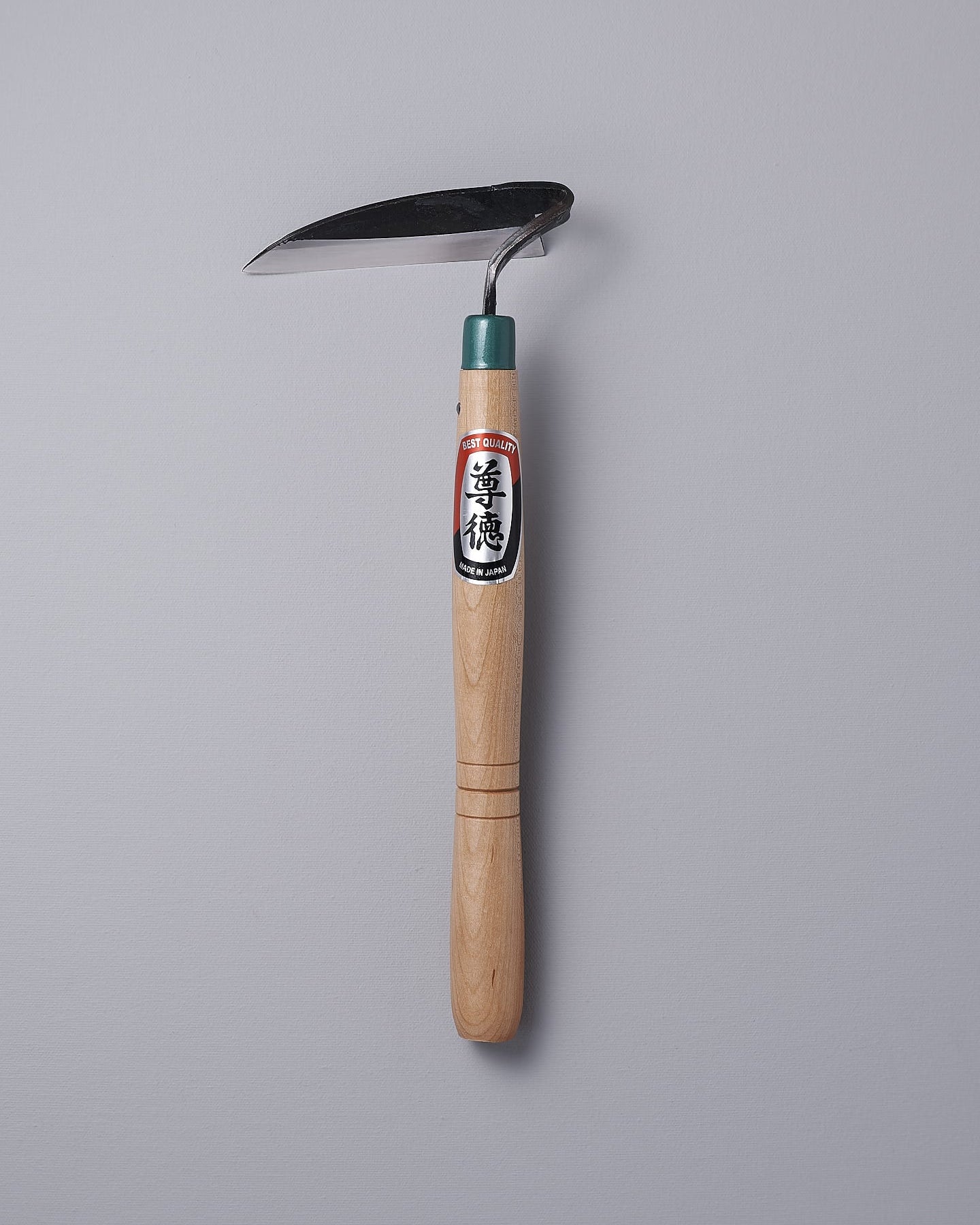 A Maruyoshi garden hoe with a green handle on a gray background.