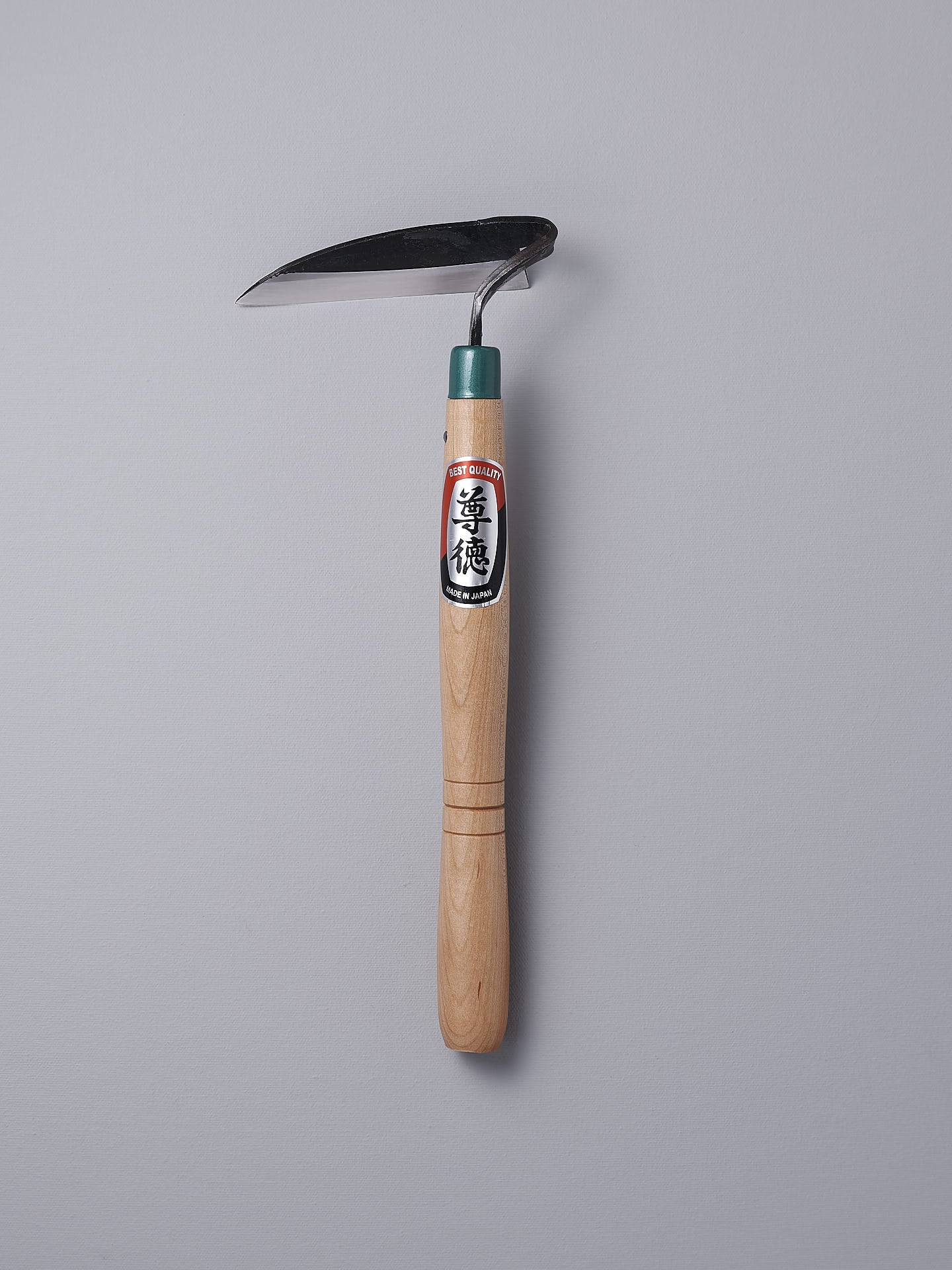 A Maruyoshi garden hoe with a green handle on a gray background.