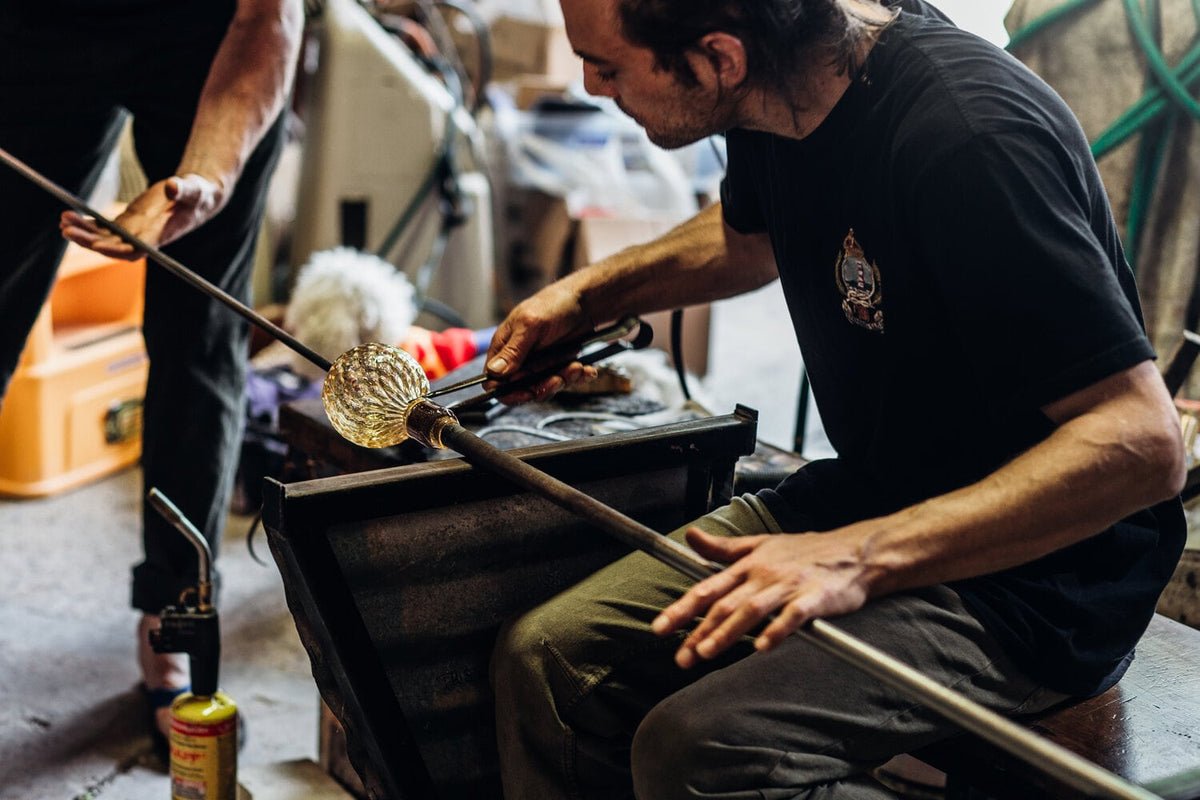 A man is working with a Matthew Hall Mini Fulvio Glass Bowl – Grey.
