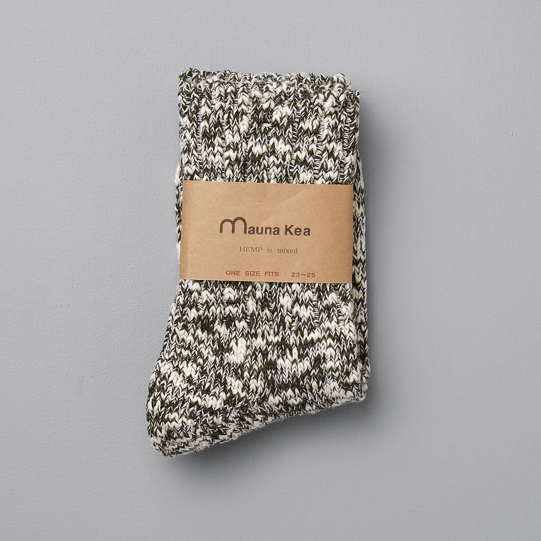 A pair of Japanese Slub Socks - Olive by Mauna Kea on a grey background.