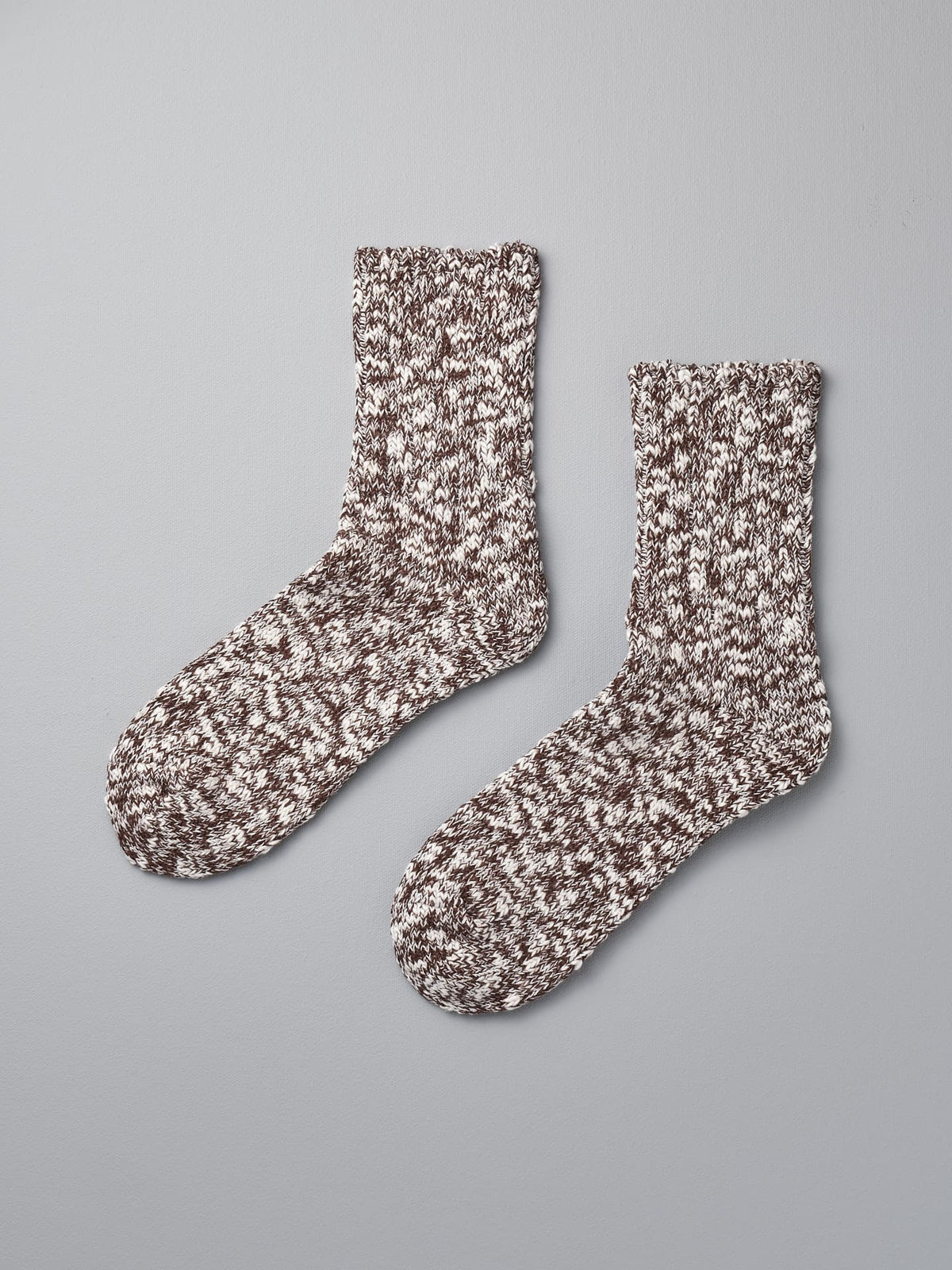 A pair of Mauna Kea Japanese Slub Socks – Brown on a grey background.