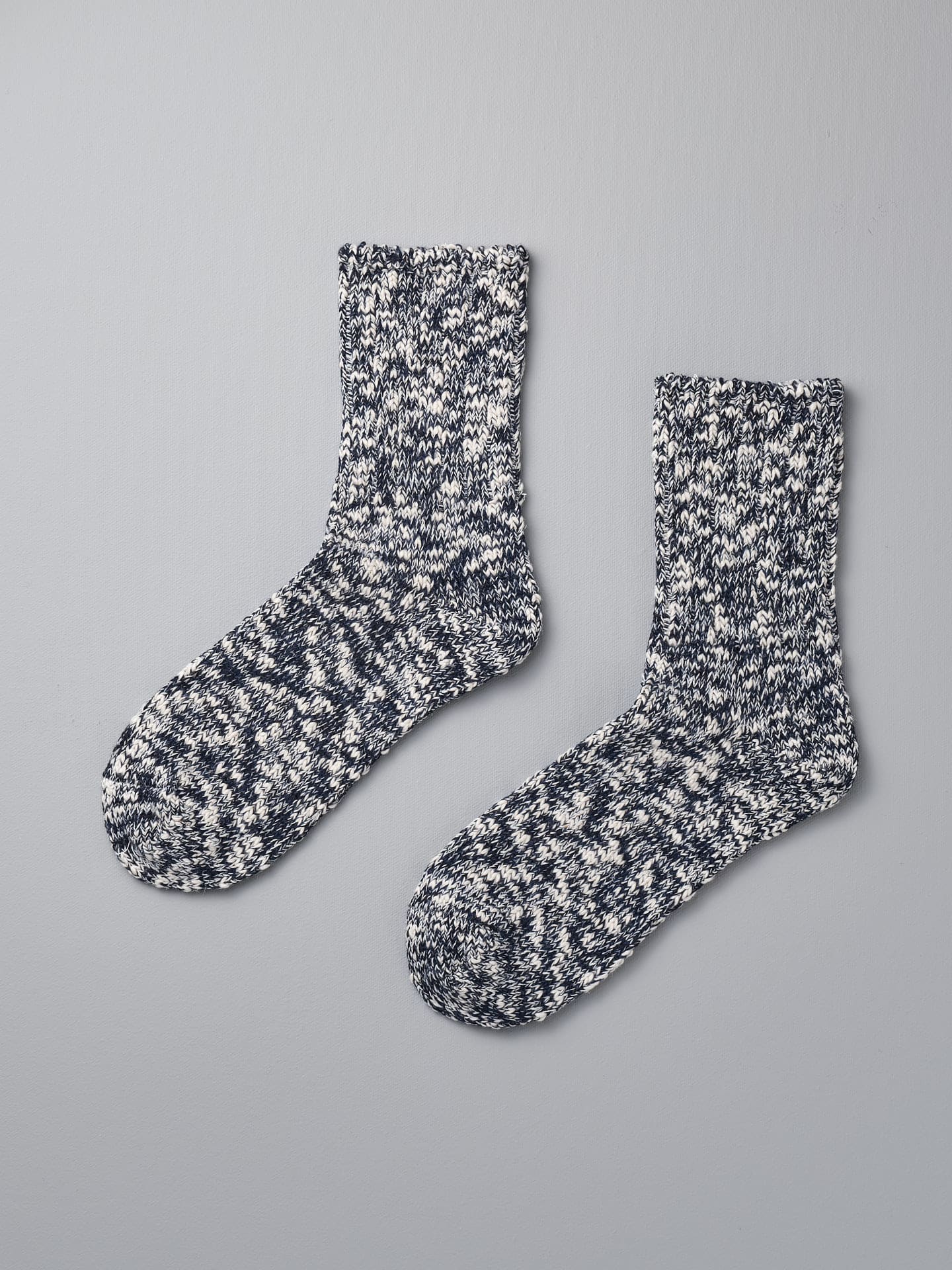 A pair of Japanese Slub Socks in navy by Mauna Kea on a grey background.
