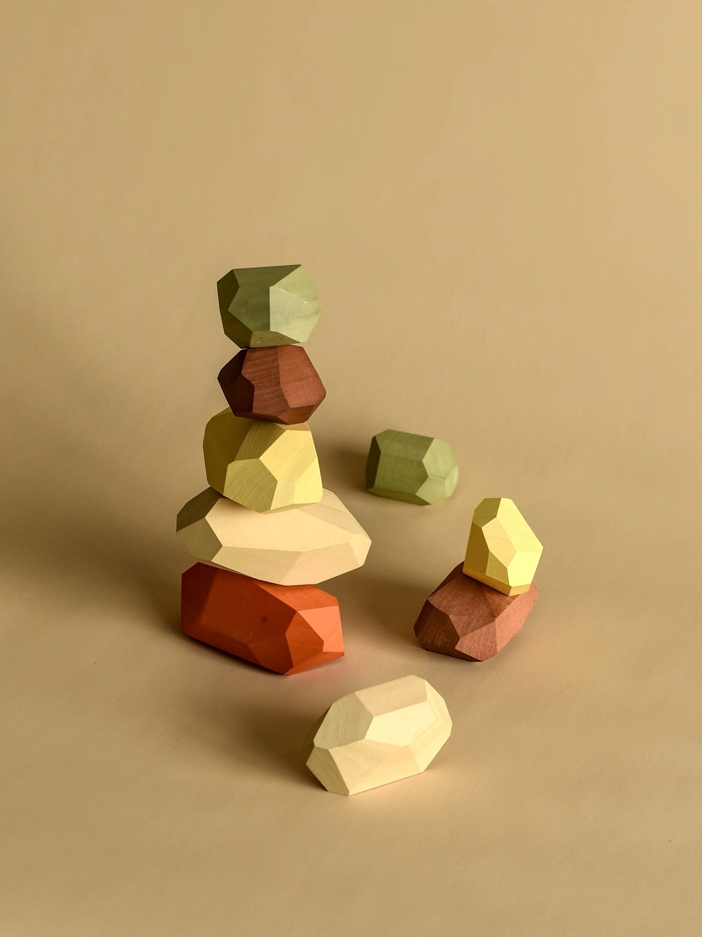 A stack of Balancing Stones - Earthy blocks on a beige background, by MinMin Copenhagen.