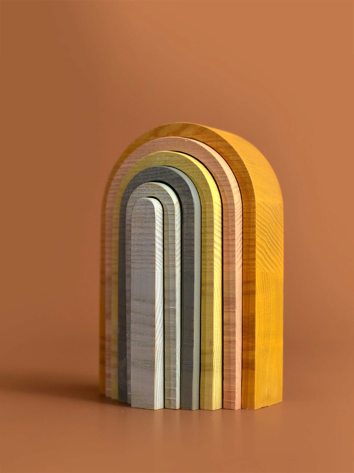 A set of Big Rainbow - Pastel wooden blocks on a brown surface by MinMin Copenhagen.