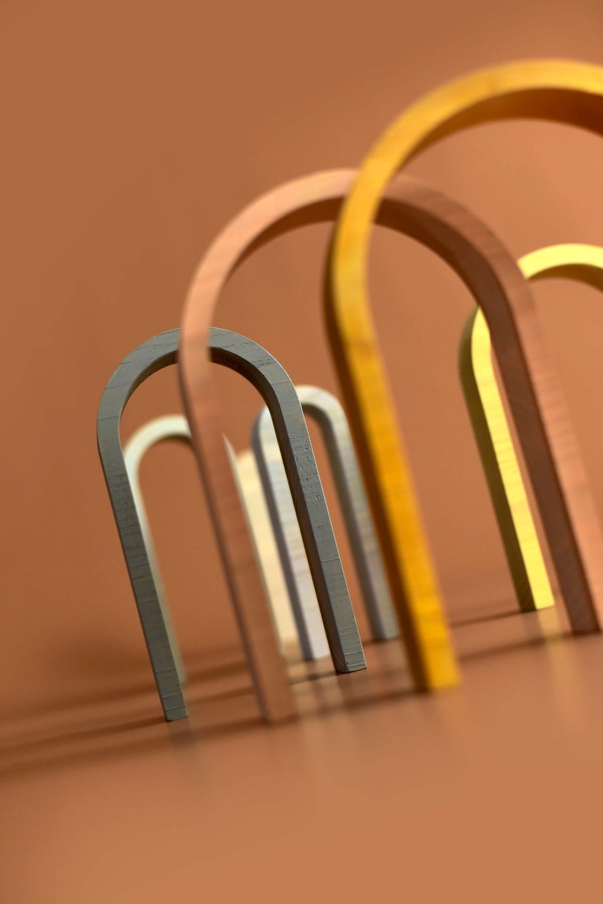 A set of Big Rainbow - Pastel wooden arches on a brown background by MinMin Copenhagen.