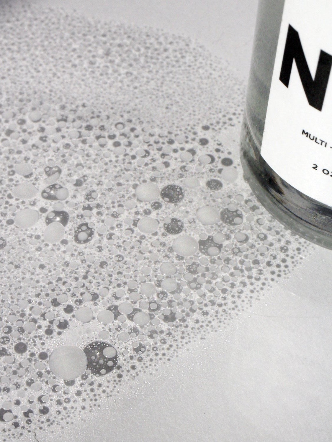 A bottle of NOTO Basil Yarrow Mist with bubbles on top of it.
