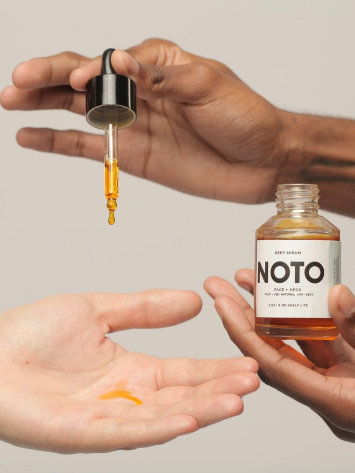 Two hands holding a bottle of NOTO Mini Deep Serum.