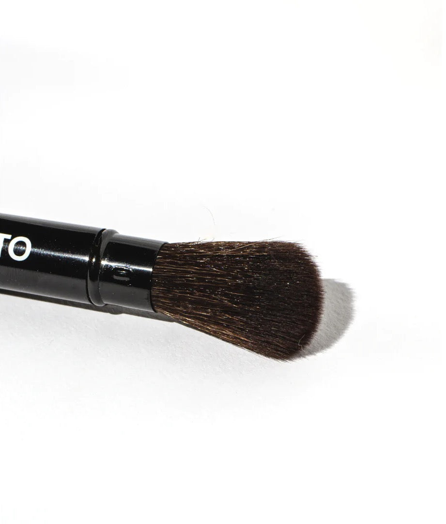 A black Lip + Cheek Duo Brush by NOTO on a white surface.