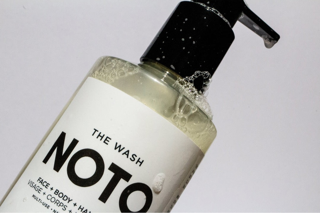 A bottle of The Wash NOTO on a white surface.