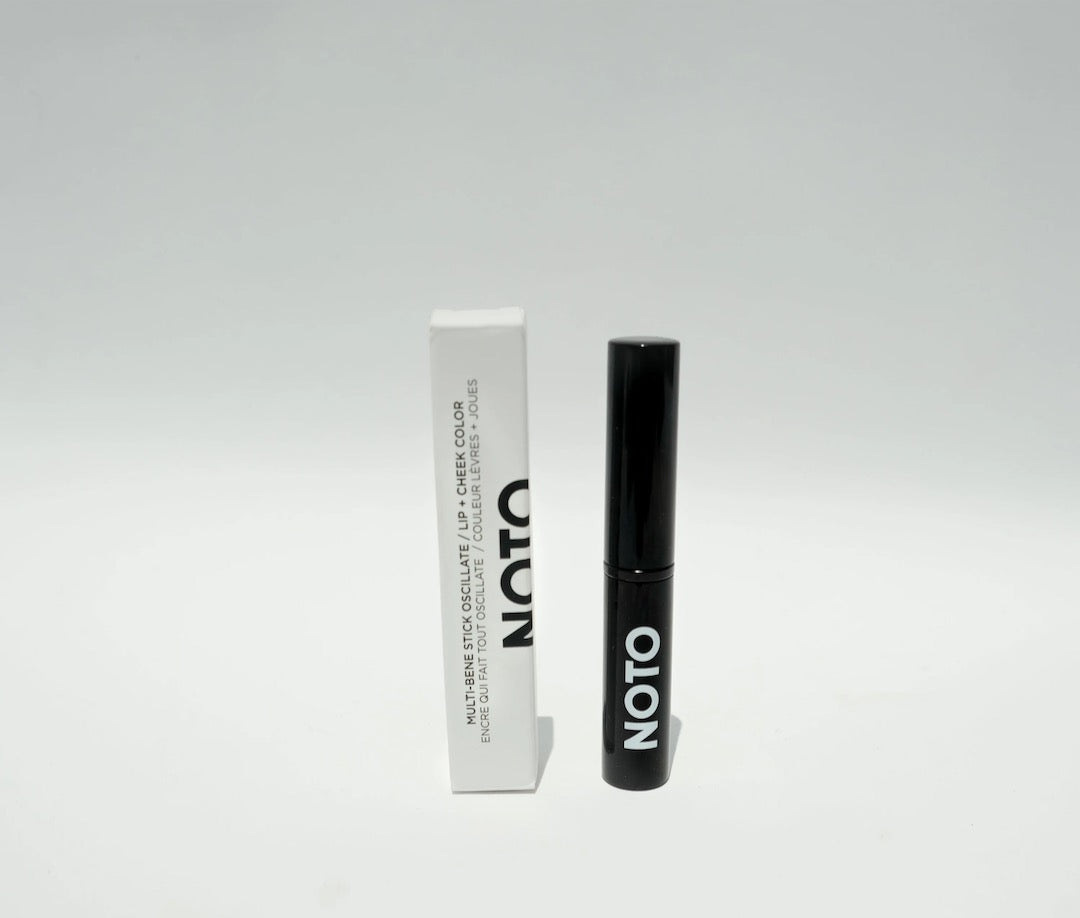 A black tube of NOTO Oscillate – Multi-Bene Stain Stick // Lips + Cheeks next to a white background.