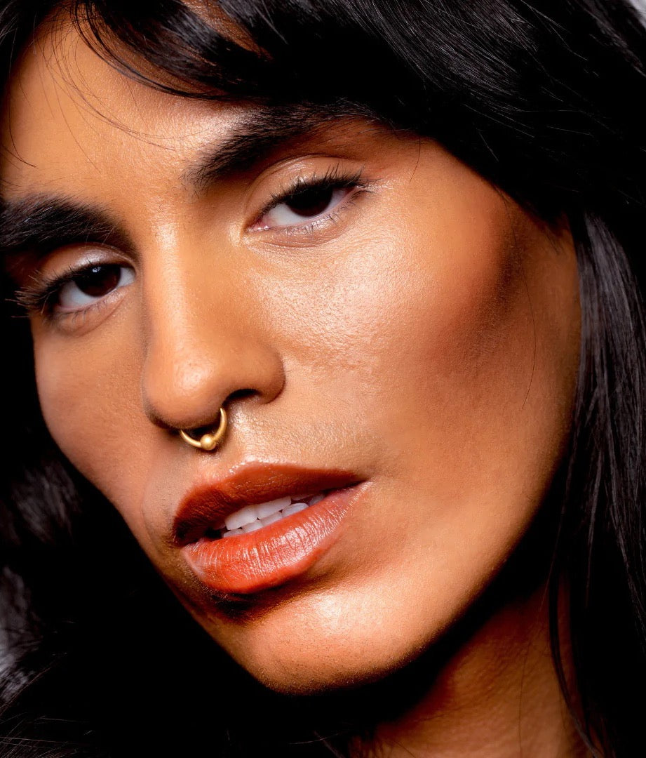 A woman with long hair and a nose piercing wearing NOTO&#39;s Fluxus – Multi-Bene Stain Stick // Lips + Cheeks.