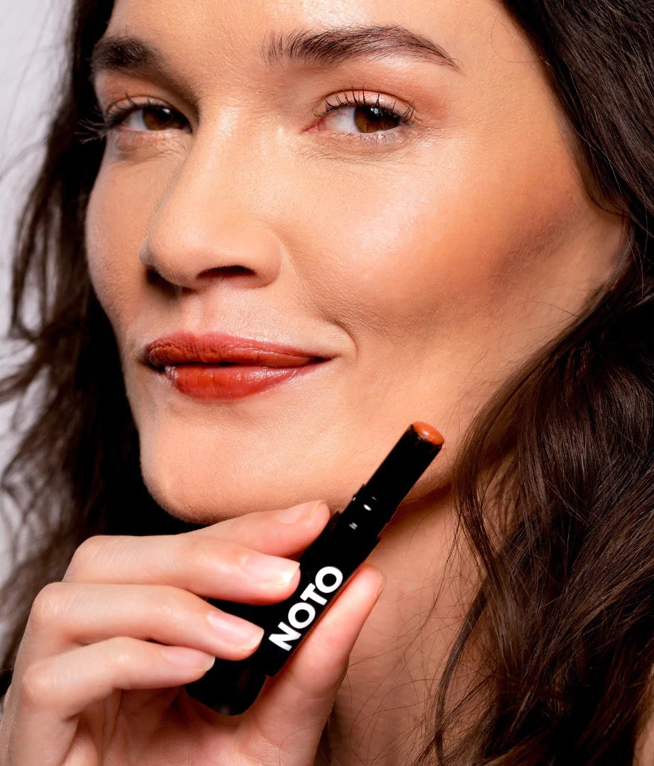 A woman is posing with NOTO&#39;s Fluxus – Multi-Bene Stain Stick on her lips.