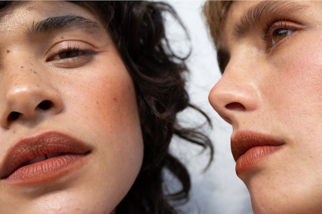 Two women are looking at each other in the NOTO Fluxus – Multi-Bene Stain Stick // Lips + Cheeks mirror.