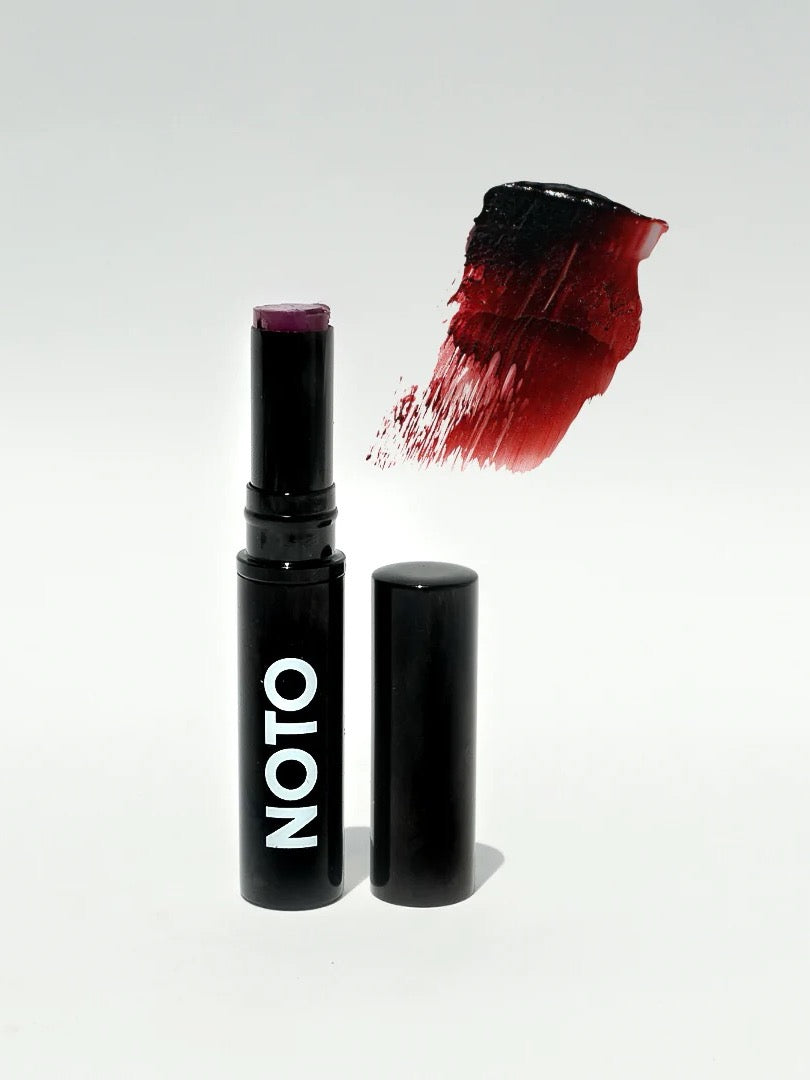 A Genet – Multi-Bene Stain Stick // Lips + Cheeks with a red color and a black cap by NOTO.