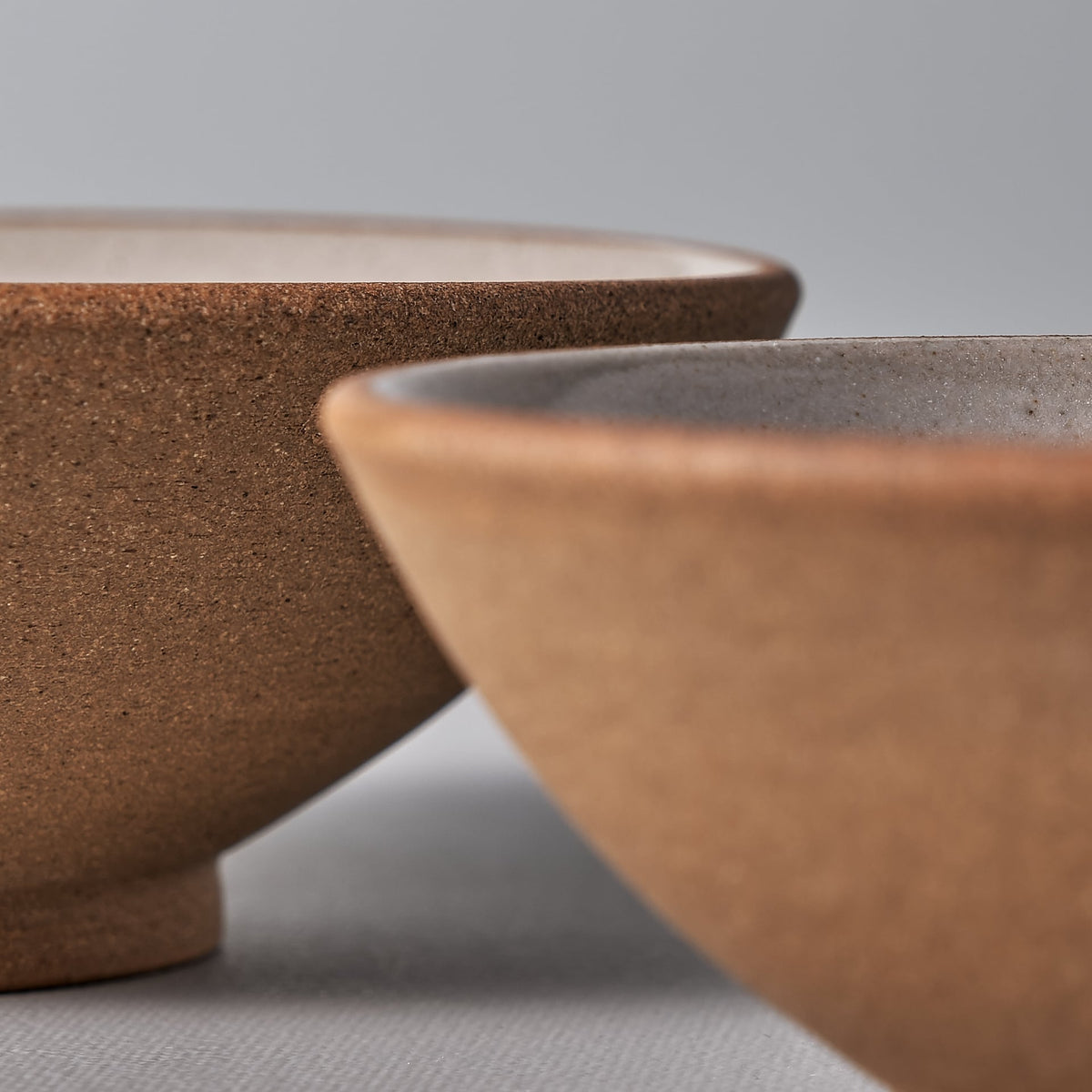 Two Nicola Shuttleworth condiment bowls on a grey surface.