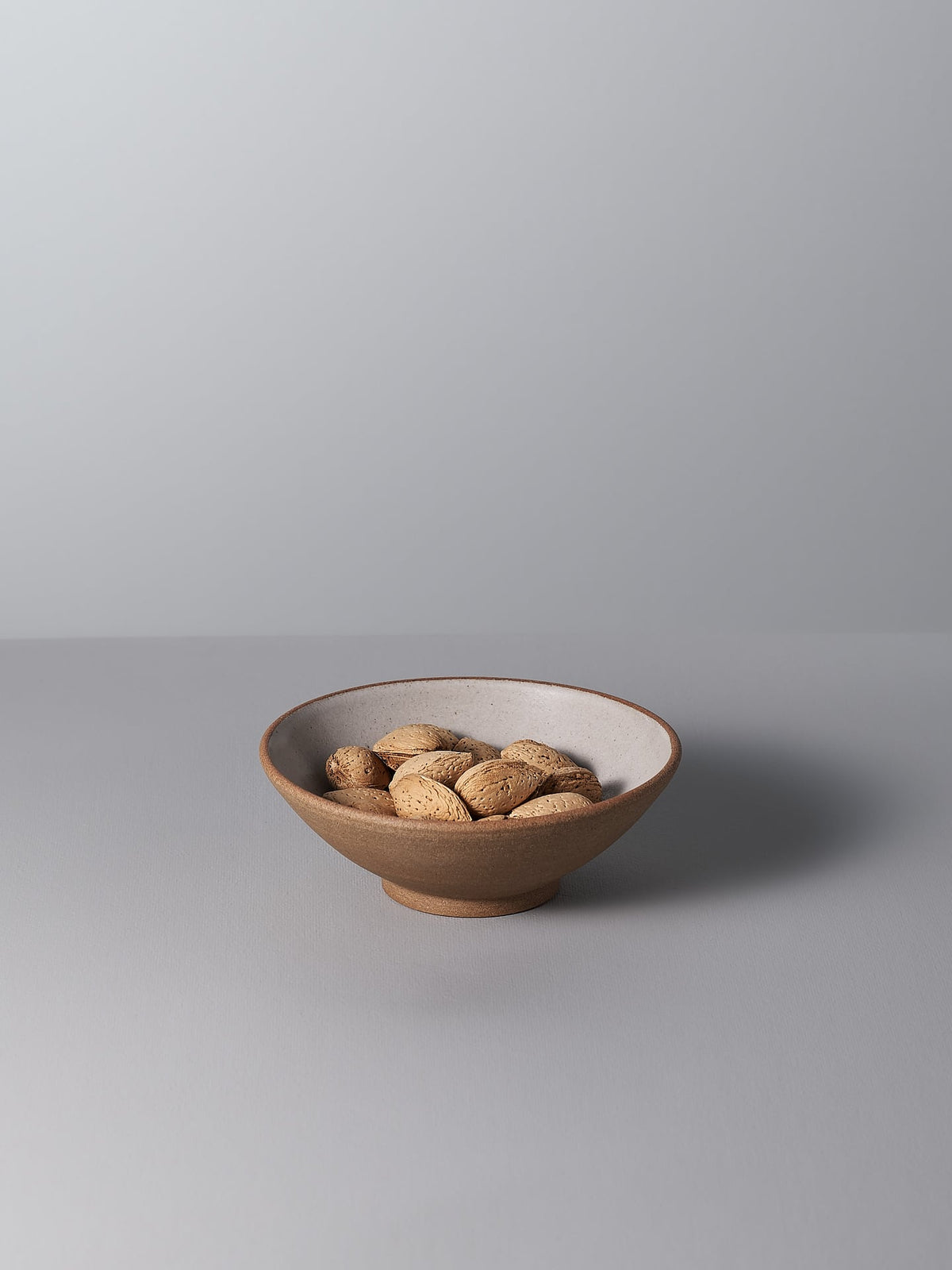 A Nicola Shuttleworth Condiment Bowl – Large filled with almonds on a grey surface.
