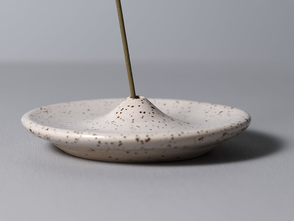 An Incense Holder – Speckled White by Nicola Shuttleworth on a white plate.
