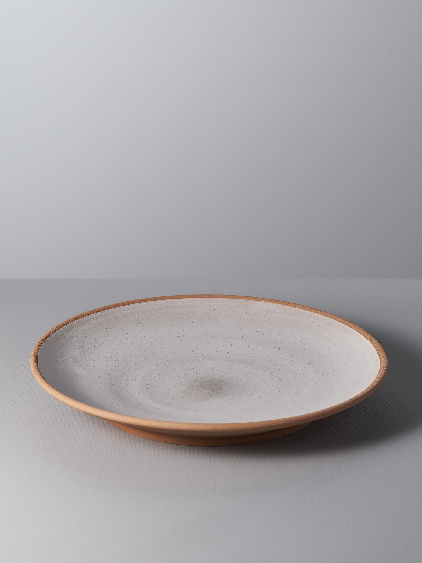 A small platter - Toast by Nicola Shuttleworth with a brown rim sitting on a grey surface.